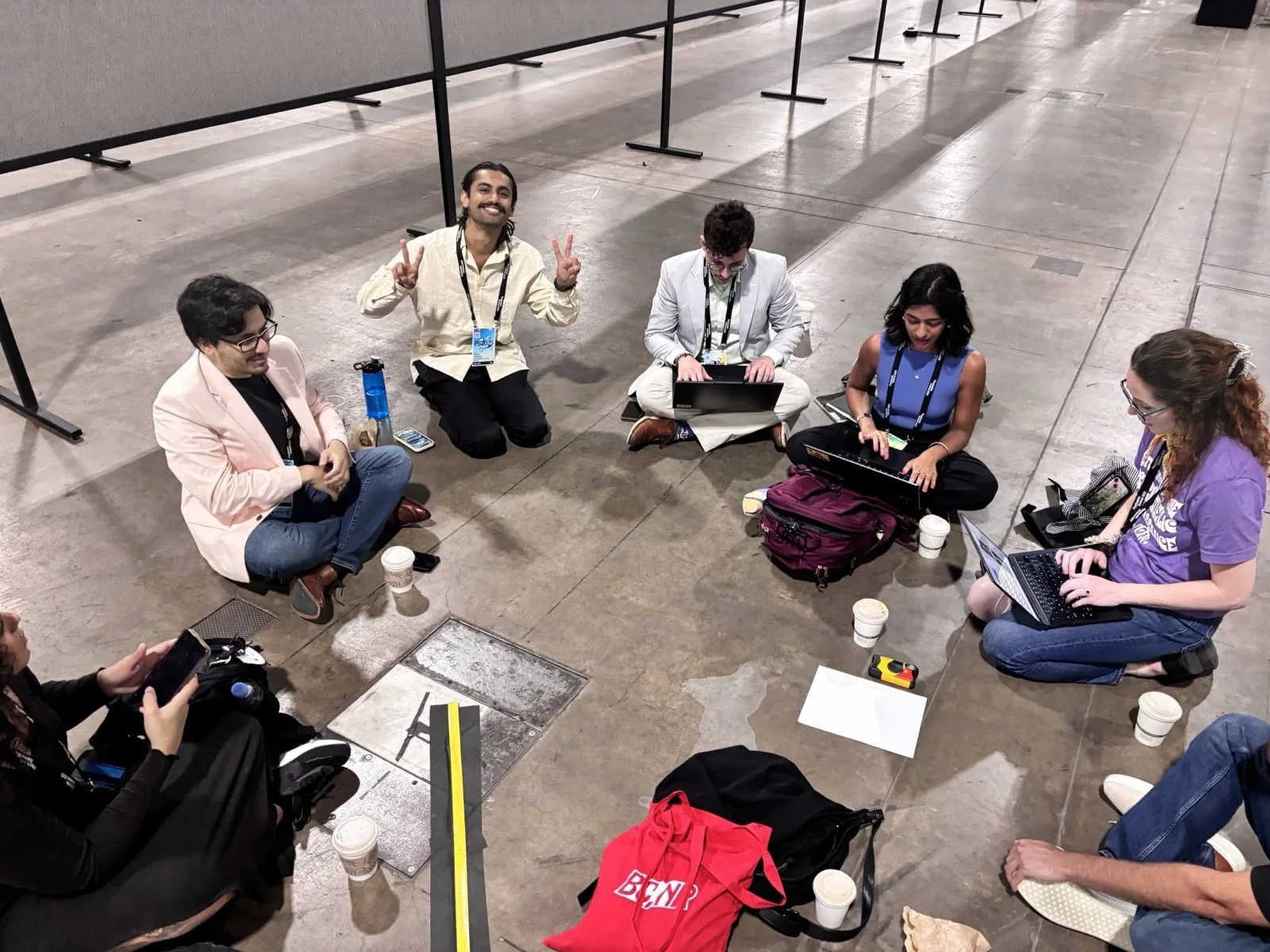 A small group seated in a circle with notebooks in a conference hallway