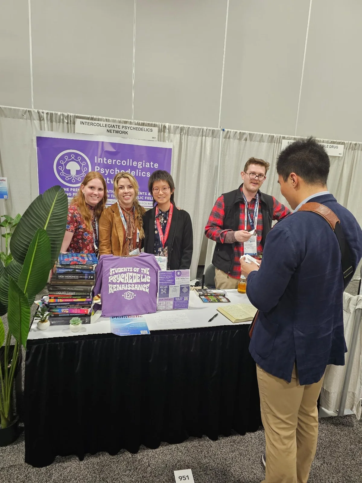IPN members talking with a visitor beside an IPN booth banner